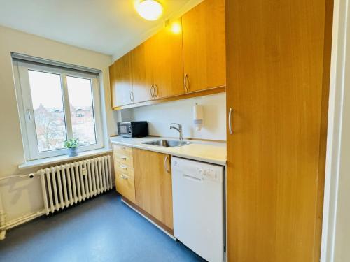 a kitchen with wooden cabinets and a sink and a window at aday - Randers Beautiful Central 2 bedrooms Apartment in Randers