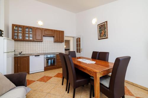 Il comprend une cuisine et une salle à manger avec une table et des chaises en bois. dans l'établissement Apartments BRANA, à Dramalj