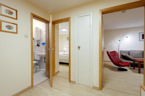a living room with a red chair and a bathroom at Haus Frier in Helgoland