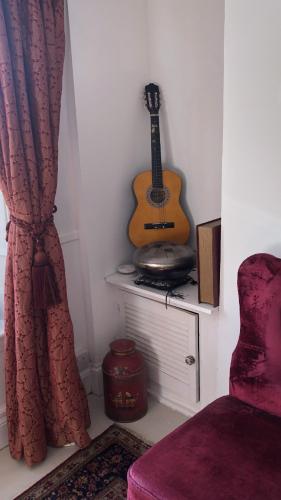 a guitar sitting on a shelf in a room with a chair at Komorebi Healing House in Dawlish
