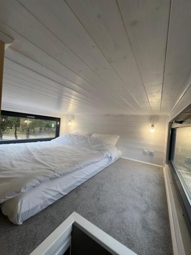 een groot wit bed in een kleine kamer met een raam bij W Sosnach in Tokarnia
