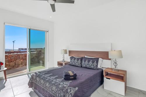 a bedroom with a bed and a large window at Casa Granito 20 - Playa Arcangel in Rosarito