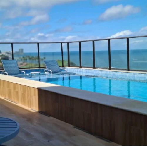 een zwembad met twee stoelen bovenop een gebouw bij Conforto próximo ao Farol in Salvador