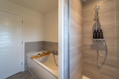 a bath tub in a bathroom with a shower at Huge Weekly & Monthly Savings - Free Parking - Wi-Fi & Netflix in Gloucester