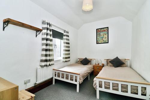 a bedroom with two beds and a window at Milk & Honey Cottage 2 Bed Ironbridge Retreat in Broseley