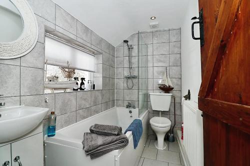a bathroom with a tub and a sink and a toilet at Milk & Honey Cottage 2 Bed Ironbridge Retreat in Broseley
