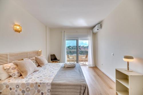 a white bedroom with a large bed and a window at golf y playa in Benalmádena