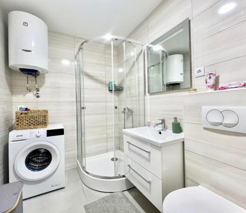 a bathroom with a shower sink and a washing machine at Danver Apartment in Bar