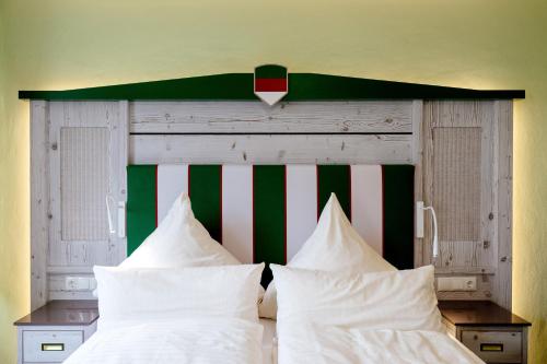 a bed with white pillows and a green and white headboard at Insulaner Ferienwohnungen in Helgoland