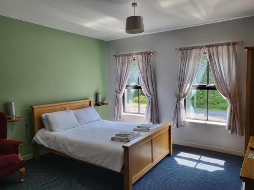 a bedroom with a bed and two windows at The Lamb & Flag in Glyn Neath