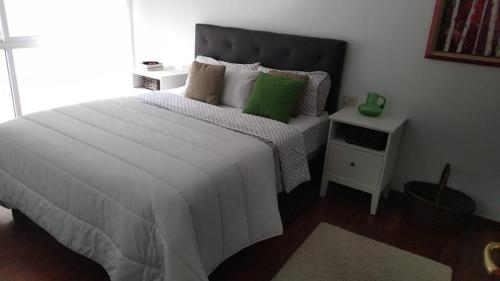 - une chambre avec un lit blanc et un oreiller vert dans l'établissement Piso con piscina próximo a Plaza de España, à Vigo