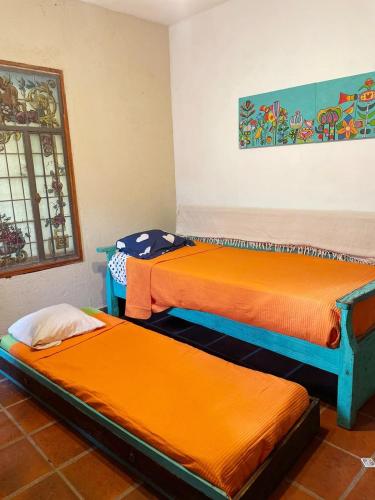 2 camas en una habitación con sábanas de color naranja en Lunas de Spilimbergo en Córdoba