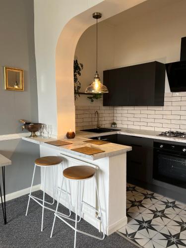 a kitchen with a counter and stools in it at Sea Spray Victorian Apartment in St. Leonards