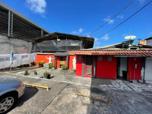 a red building with a car parked in a parking lot at Pousada ACRÓPOLE in Belém