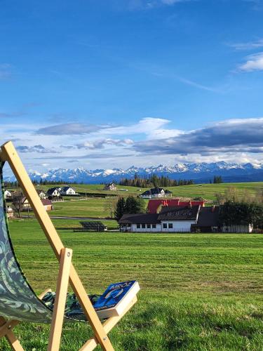 a lawn chair sitting in a field with a house at Domki Na Grapie - z widokiem na Tatry in PyzÃ³wka