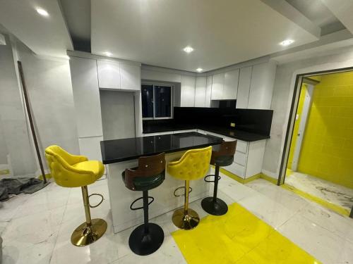uma cozinha com bancos de bar amarelos e um balcão preto em Luxury Room SC em San Cristóbal