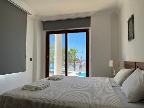 a white bedroom with a bed with two towels on it at Villa Deniz in Kalkan