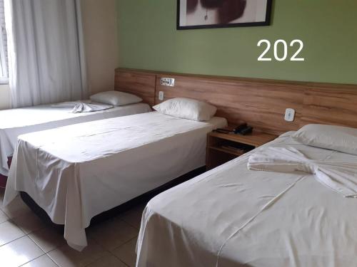 duas camas num quarto de hotel com o número em HOTEL PRINCIPE em Governador Valadares