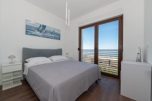 a white bedroom with a bed and a large window at Villa Hillson in Makarska