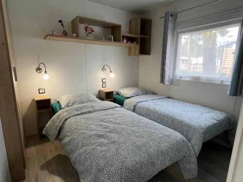 une chambre avec deux lits et une fenêtre dans l'établissement Domaine de Kerlann - Mobilhome refait à neuf- 40m2 - service de conciergerie et lits faits OFFERTS, à Pont-Aven
