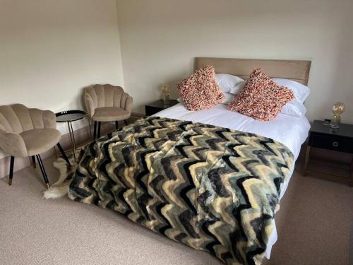 a bedroom with a bed with a blanket and chairs at Cosy hideaway in leafy Lytham in Lytham St Annes
