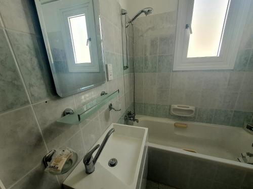 bagno con lavandino, vasca e specchio di G&E HARBOUR MAISONETTE NUMBER 13 a Lachi