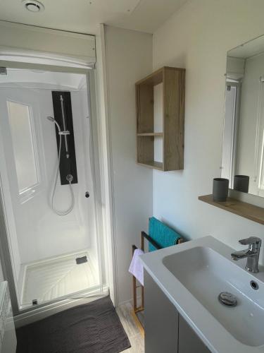La salle de bains est pourvue d'un lavabo et d'une porte. dans l'établissement Domaine de Kerlann - Mobilhome refait à neuf- 40m2 - service de conciergerie et lits faits OFFERTS, à Pont-Aven