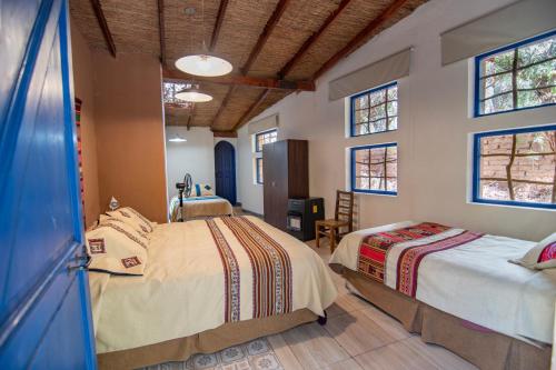 a bedroom with two beds and two windows at Ckoi Atacama Lodge in San Pedro de Atacama