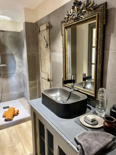 une salle de bain avec un lavabo noir et un miroir dans l'établissement Le Mas Saint Philippe, à Jonquières