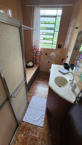 a bathroom with a sink and a shower stall at Hostel Lumaria 1 in Blumenau