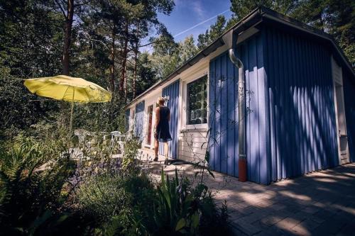 Uma mulher à porta de um barracão azul em Gemütliches Ferienhaus für bis zu 4 Personen-Urlaub machen, wo der Weihnachtsmann zu Hause ist em Fürstenberg-Havel
