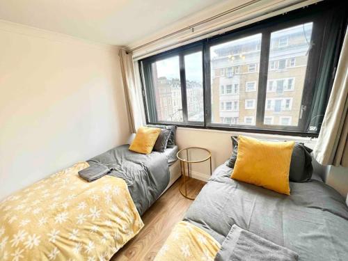 1 Schlafzimmer mit 2 Betten und einem großen Fenster in der Unterkunft LUXstay 2BR Earls Court Apartment Sleeps up to 10 in London