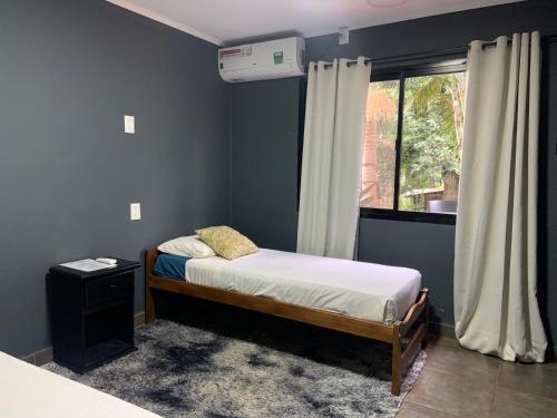niewielka sypialnia z łóżkiem i oknem w obiekcie Ambar House Apart w mieście Puerto Iguazú
