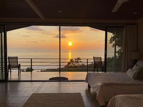 a bedroom with a view of the ocean at sunset at Villa Del Mar 2 Spectacular ocean view! in Dominical