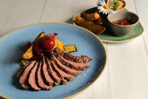 a blue plate of food with meat and vegetables at Hotel Sempachersee in Nottwil