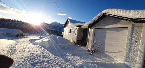 a house covered in snow with the sun behind it at JULIA in Myre