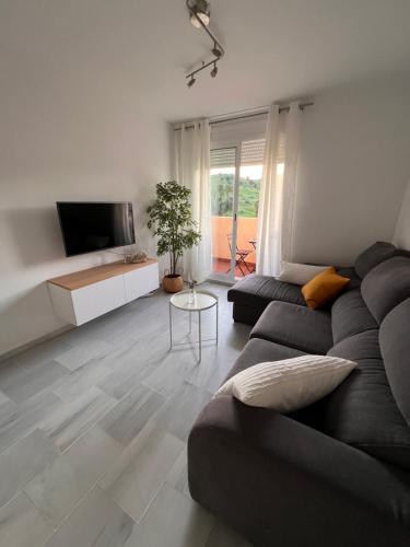a living room with a couch and a tv at Apartamento Jardín de Atalaya in Camas