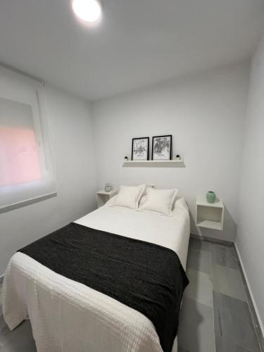 a white bedroom with a bed with a black blanket at Apartamento Jardín de Atalaya in Camas