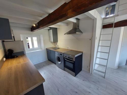 une cuisine avec une cuisinière et une machine à laver dans l'établissement Appt lumineux, vue place Vival, à Figeac