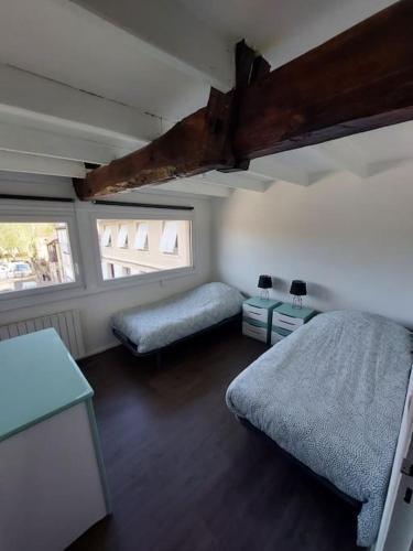 une chambre avec deux lits et deux fenêtres dans l'établissement Appt lumineux, vue place Vival, à Figeac