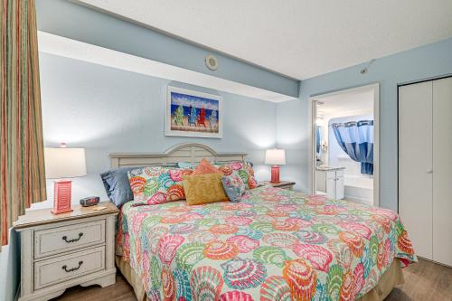 a bedroom with a bed with a colorful bedspread at Beachy Condo with Pool Access and Steps to Boardwalk! in Myrtle Beach