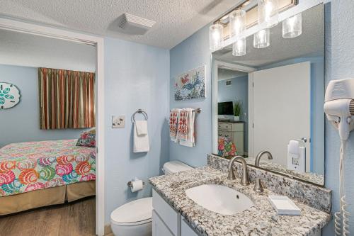 a bathroom with a sink and a toilet and a bed at Beachy Condo with Pool Access and Steps to Boardwalk! in Myrtle Beach