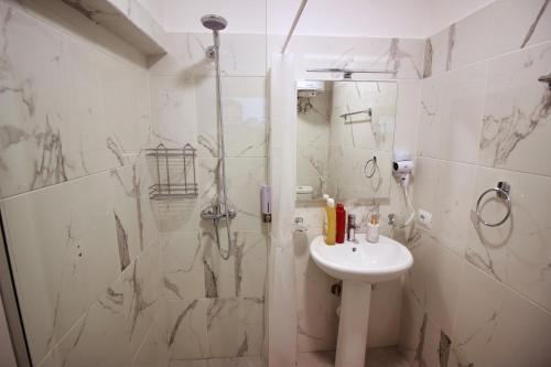 a white bathroom with a shower and a sink at Emblematic House Apartment 4 in Gjirokastër
