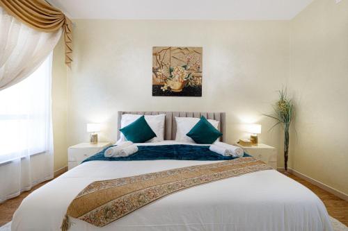 a bedroom with a large bed with green and white pillows at Stylish and Sleek: Modern Well-Furnished One Bedroom Hall and Kitchen Apartment in Dubai