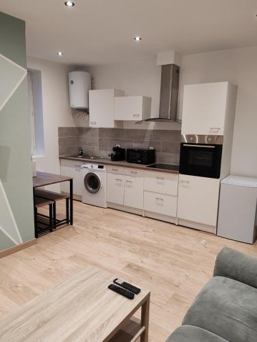 une cuisine avec des armoires blanches, une table et un canapé dans l'établissement Appartement 40 m2, à Saint-Étienne