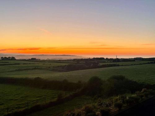 a sunset over a green field with the sun setting at Carnbore House BnB in Bushmills