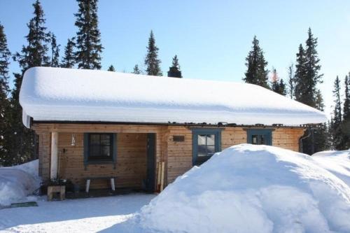 a house covered in snow with a pile of snow at Gemütliches neu erbautes Blockhaus mit Kamin im Oviksfjäll in Galåbodarna