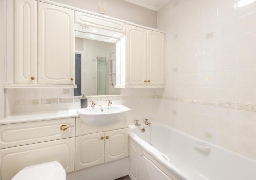 a white bathroom with a sink and a bath tub at Mews Cottage in Grasmere