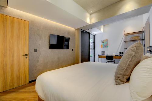 a bedroom with a white bed and a tv on a wall at Park Condesa by Capitalia in Mexico City