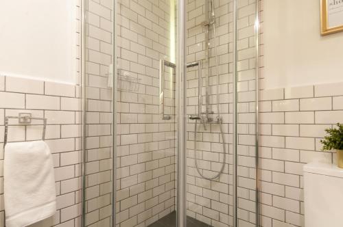 y baño con ducha y paredes de azulejos blancos. en Casa PILAR Central By MyRentalHost, en Barcelona